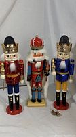 Photo showing trio of three wooden nutcrackers standing side by side, showing full height and details