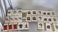 Wide view of 20 Hallmark Christmas ornaments mostly in original boxes showing varying designs and packaging wear