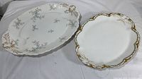 Two oval Haviland & Co Limoges serving plates side by side. Both have gilded edges and floral decorations.