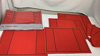 Two Tiffany placemat and napkin sets boxed and unboxed, showing red color with black accents and napkins in coordinated red fabric.