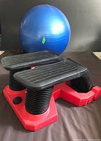 Close-up photo of the Air Climber Express Stepper focusing on black pedals with textured surface and red base, placed on a dark surface