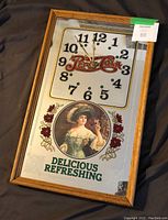 Full view of Pepsi-Cola mirrored wall clock showing the clock face, logo, vintage woman image and wooden frame.
