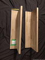 Two pine wood wall shelves shown flat on a black surface with measuring tape for scale, displaying top and side views to depict dimensions and structure.
