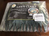 Photo of Lawn Claws leaf scoops in original packaging showing product style 45TA and features like elastic handle strap and wipe-clean surface.