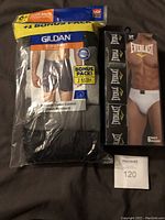 Package of Gildan boxer briefs showing multiple colors including gray, black, and white. Packaged as a 6 plus 1 bonus pack of cotton comfort briefs, size small.