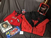 Photo of the entire collection showing jacket, apron, collectible card, DVD, metal tray and sign.