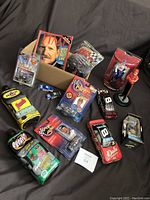 Photo of the lot including various NASCAR diecast cars, two quarts of motor oil, Dale Earnhardt memorabilia, and a TIME Magazine memorial edition.