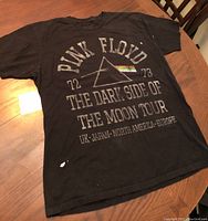 Full view of the Pink Floyd black cotton tour T-shirt displaying front design with minor paint stains.