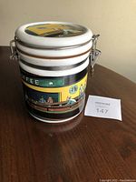 Side view of Starbucks ceramic coffee container with illustrated coffeehouse scene and locking lid.