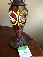 Close-up of the stained glass Tiffany style lamp base with brightly colored glass pieces in red, yellow, and blue on bronze base with ornate detailing.