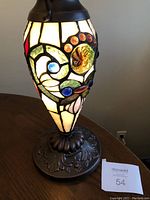 Lamp showing stained glass pattern with colorful jewels illuminated on ornate base
