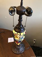 Full view of the lamp showing the base, two bulb sockets with pull chains, and the stained glass floral lighted body.