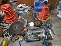 Wide shot of the lot showing air hoses coiled, circular saw blades, Norton sanding sheets, hand tools including clamps and screwdrivers, and spray grease gun.