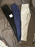 Three pairs of women's tights laid out, showing color and style: black, navy blue, and light gray.