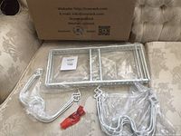 Unassembled white metal dividers and rack components laid out on a couch with original packaging box behind.