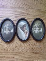 Front view of three miniature oval photographs in metal frames showing vintage portraits of two children and a mother with child