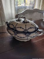 Side view of the blue and white decorated lidded vegetable server showing shape and handle details.
