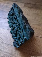 Detailed view of the side and carved top surface of one wooden fabric stamp block showing intricate floral pattern and wear marks.