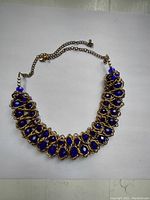 Full view of necklace showing blue stones linked by brass wire and brass chain ends.