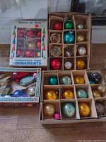 Four boxes of vintage Christmas ornaments including glass balls in various colors and designs, plus a box of plastic ornaments with Santa figures