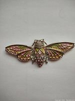 Front view of the large bee-shaped brooch showing detailed enamel and rhinestone decoration in pink, green, and clear colors.
