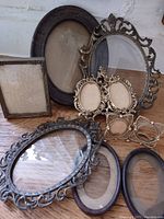 Group of antique brass and metal photo frames arranged together showing various sizes and ornate details