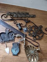 Various vintage metal pieces including decorative metal strips with rose designs, a rusty saw blade, souvenir metal items, ornamental components, and a small metal wheel.