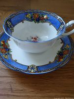 Teacup displaying inside floral pattern and detailed blue border accompanied by saucer