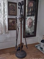 Full view of the caged fireplace tool set with stand and figurine on top, including three tools hanging.