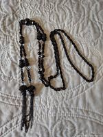 Closer view of the necklace laying in loose loops, highlighting the clustered faceted beads and chain tassels.