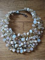Photo showing full vintage beaded collar necklace laid flat on a wooden surface with clasp closure visible.