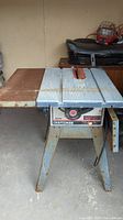 Full view of Craftsman 10-inch table saw showing metal tabletop with attached extension and stand with rust.
