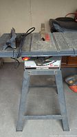 Overall view of table saw showing working surface, power cord, and metal frame stand.