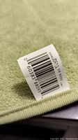 Close-up photo of the green bathroom floor towel showing its texture and attached barcode tag