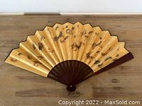 Full view of the fan open laid flat showing dragon artwork and overall design.