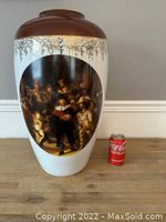 Full view of tall porcelain vase showing painted group portrait and brown rim with decorative silver border at top. Coca-Cola can shown for scale.