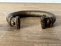 Side view of brass coil bracelet showing sculpted ends and coil detail