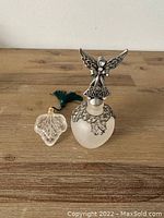 Two frosted glass perfume bottles; larger with angel stopper, smaller with leaf stopper and tassel