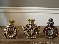 Photo showing the three Czech glass perfume bottles side by side highlighting their shapes and gem-studded gold filigree decoration.