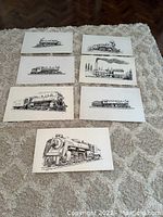 Full overview of all 7 train sketches laid out on carpet by seller