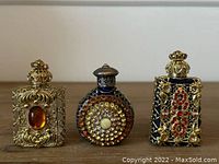 Three Czech glass perfume bottles with gold-tone filigree and colorful stones, shown side by side.