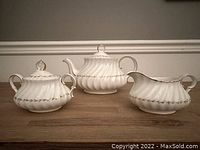 Group photo of the teapot, creamer, and sugar bowl showing the white swirled shape with gold gilded trim