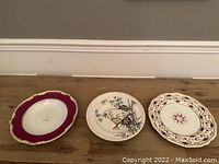 Three antique English porcelain plates, one red-bordered with gold accents, one with bird and bamboo painted scene, one pierced with floral center.