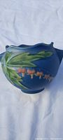 Blue antique Roseville pottery vase with raised green leaf and orange flower design front view