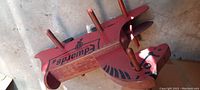 Top angle view of antique wooden rocking horse showing branding, original paint, and wooden handles and pegs for stability and grip.
