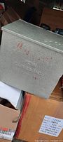 Front view of gray insulated milk bottle porch box displaying embossed 'PENN DAIRIES INC.' with faint red lettering on textured surface.