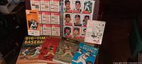 View showing sheets of vintage baseball cards, the Baseball Dope Book publication, and an array of mid-century baseball books including Big-Tim Baseball and Secrets of the Big Leagues.