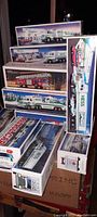 Photo showing stacked boxes of various older Hess trucks showcasing their original packaging and detailed illustrations.