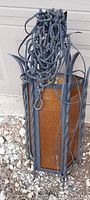 Original mid-century hanging lamp with cast steel frame and amber colored panels, showing twisted rods and hanging chain with attached wiring.