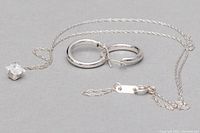 Chain, pendant, and hoop earrings arranged on neutral surface